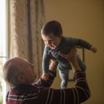 grandpa holding baby in multigenerational living arrangement