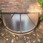 egress window well cover surrounded by fallen leaves