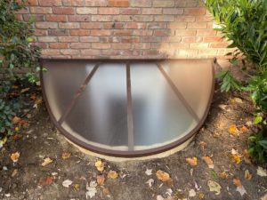 egress window well cover surrounded by fallen leaves window well maintenance egress solutions